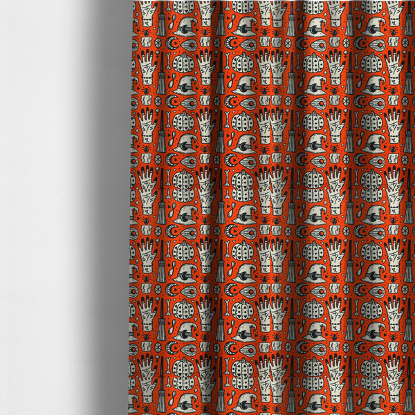 The fabric used to create these made-to-measure curtains is an orange Halloween fabric patterned with repeating black and white illustrations of patterned pumpkins, mystical hands with symbols, witch hats with crescent moons, brooms, candles, bones, and planchettes.