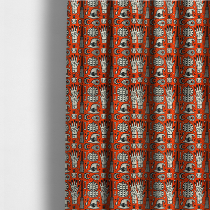 The fabric used to create these made-to-measure curtains is an orange Halloween fabric patterned with repeating black and white illustrations of patterned pumpkins, mystical hands with symbols, witch hats with crescent moons, brooms, candles, bones, and planchettes.
