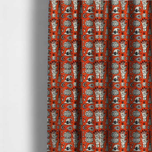 The fabric used to create these made-to-measure curtains is an orange Halloween fabric patterned with repeating black and white illustrations of patterned pumpkins, mystical hands with symbols, witch hats with crescent moons, brooms, candles, bones, and planchettes.