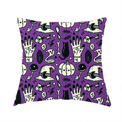 The fabric used to create this handmade cushion is a purple Halloween fabric patterned with repeating black and cream illustrations of pumpkins, witch hats, black cats, mystical marked hands, snakes, keys, bones, and crystals.
