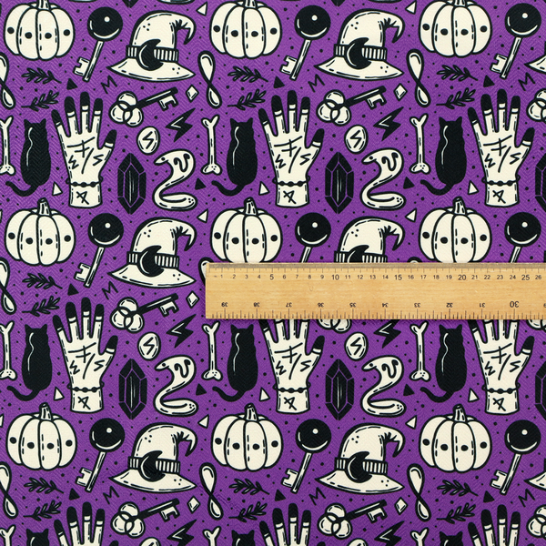 A purple Halloween fabric patterned with repeating black and cream illustrations of pumpkins, witch hats, black cats, mystical marked hands, snakes, keys, bones, and crystals.