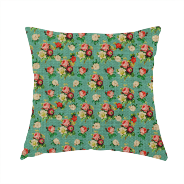 The fabric used to create this handmade cushion is a charming repeating pattern of small bouquets featuring pink and red roses paired with white blossoms and green leaves set against a textured teal background.
