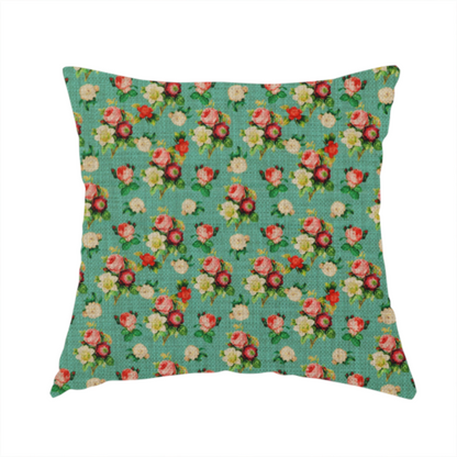The fabric used to create this handmade cushion is a charming repeating pattern of small bouquets featuring pink and red roses paired with white blossoms and green leaves set against a textured teal background.
