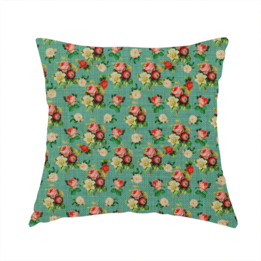 The fabric used to create this handmade cushion is a charming repeating pattern of small bouquets featuring pink and red roses paired with white blossoms and green leaves set against a textured teal background.