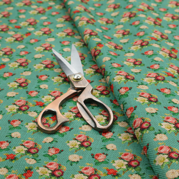 A charming repeating pattern of small bouquets featuring pink and red roses paired with white blossoms and green leaves set against a textured teal background.
