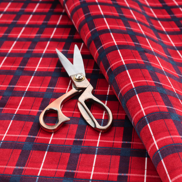 A vibrant red plaid and tartan pattern featuring intersecting dark blue and white stripes over a bold red background.
