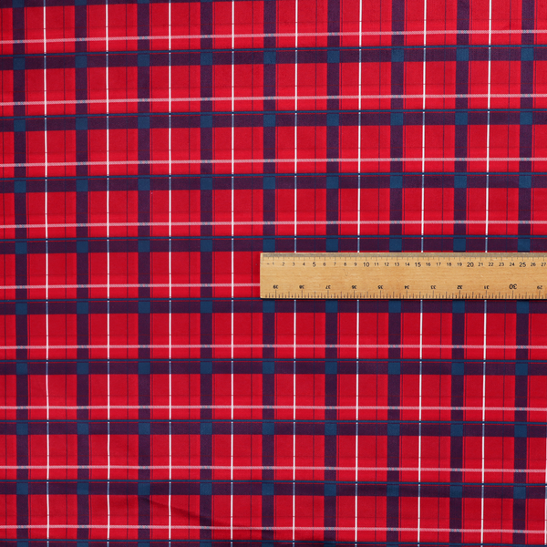 A vibrant red plaid and tartan pattern featuring intersecting dark blue and white stripes over a bold red background.