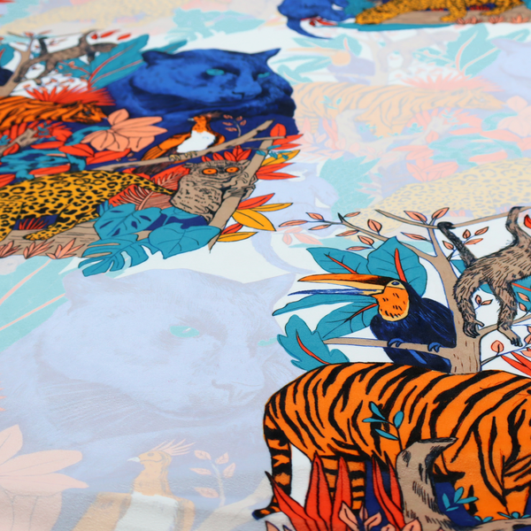 A colourful and vibrant jungle pattern on a pale background featuring a blue panther, tigers, leopards, monkeys, toucans, and lush tropical flora.