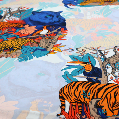 A colourful and vibrant jungle pattern on a pale background featuring a blue panther, tigers, leopards, monkeys, toucans, and lush tropical flora.