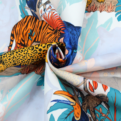 A colourful and vibrant jungle pattern on a pale background featuring a blue panther, tigers, leopards, monkeys, toucans, and lush tropical flora.