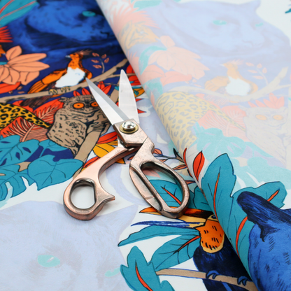 A colourful and vibrant jungle pattern on a pale background featuring a blue panther, tigers, leopards, monkeys, toucans, and lush tropical flora.
