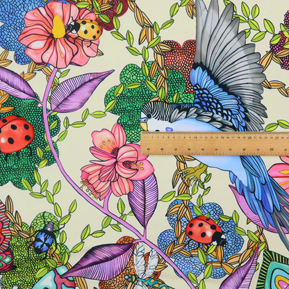 A colourful and detailed repeating pattern on a light background featuring blue and yellow birds, bright butterflies, ladybugs, and vibrant pink flowers.