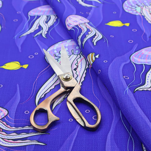 A vibrant underwater pattern on a rich blue background featuring glowing purple and pink jellyfish, tiny colourful fish, and floating bubbles.