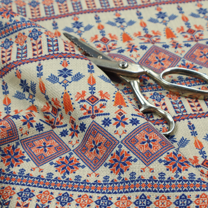 Intricate folk-inspired fabric featuring horizontal bands of geometric diamonds, stylized birds, and floral motifs in navy blue and rust orange on a beige background.
