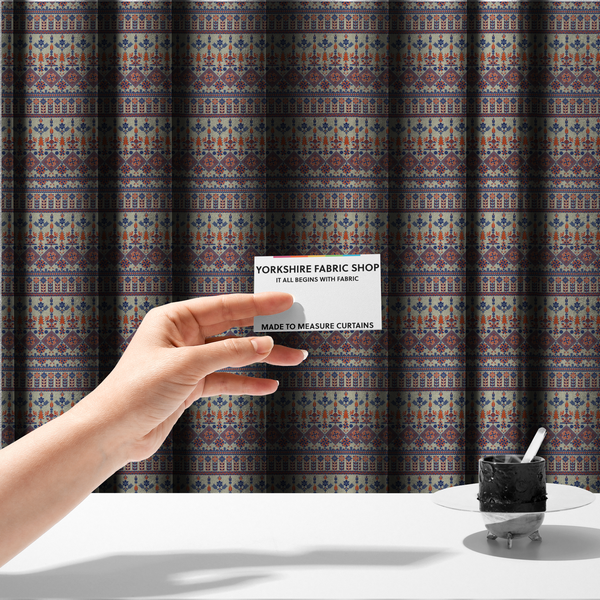 The fabric used to create these made-to-measure curtains is a intricate folk-inspired fabric featuring horizontal bands of geometric diamonds, stylized birds, and floral motifs in navy blue and rust orange on a beige background.