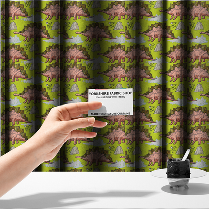 The fabric used to create these made-to-measure curtains is a repeating pattern on a vibrant green background featuring pink Stegosaurus dinosaurs with golden plates, interspersed with light grey rocks, fluffy white clouds, and small green sprigs.