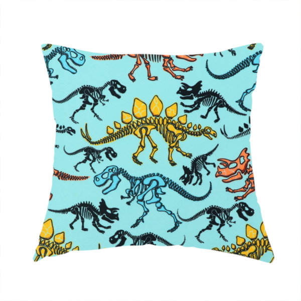 The fabric used to create this handmade cushion is a repeating pattern on a light blue background featuring colourful dinosaur skeletons in yellow, orange, blue, and black, depicting various species including Stegosaurus, Triceratops, and Tyrannosaurus rex.
