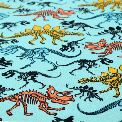 A repeating pattern on a light blue background featuring colourful dinosaur skeletons in yellow, orange, blue, and black, depicting various species including Stegosaurus, Triceratops, and Tyrannosaurus rex.