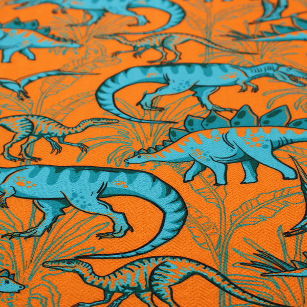 A repeating pattern on a bright orange background featuring blue dinosaurs, including Stegosaurus, T-Rex, and pterosaurs, set against a backdrop of palm leaves and tropical foliage.