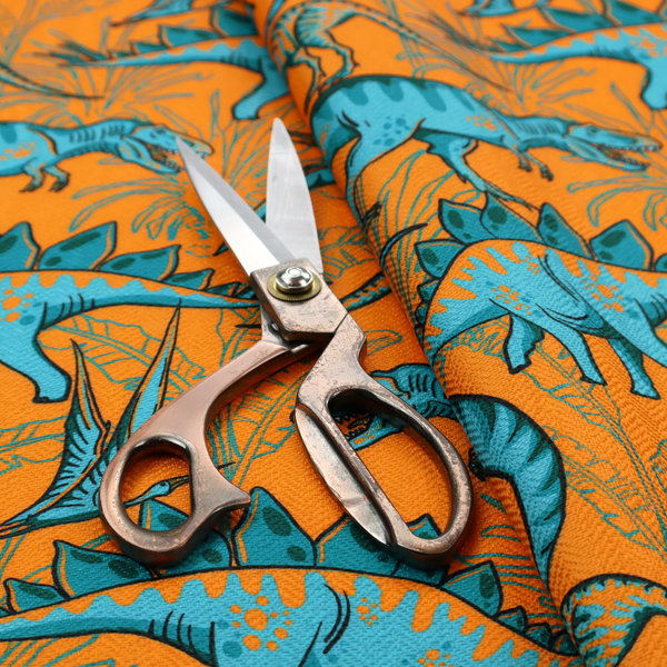 A repeating pattern on a bright orange background featuring blue dinosaurs, including Stegosaurus, T-Rex, and pterosaurs, set against a backdrop of palm leaves and tropical foliage.