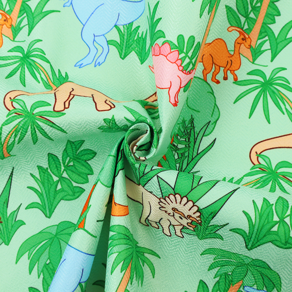 A repeating pattern on a light green background featuring colourful illustrated dinosaurs—including blue T-Rexes, pink Stegosauruses, beige Triceratopses, and orange sauropods—surrounded by green palm trees, bushes, and tropical foliage.
