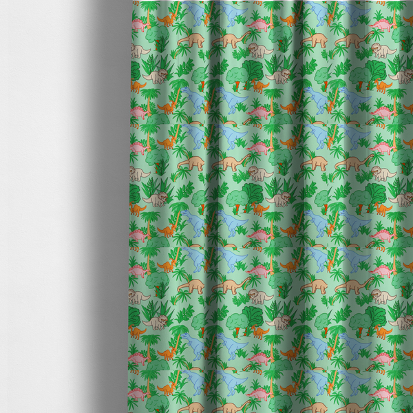 The fabric used to create these made-to-measure curtains is a repeating pattern on a light green background featuring colourful illustrated dinosaurs—including blue T-Rexes, pink Stegosauruses, beige Triceratopses, and orange sauropods—surrounded by green palm trees, bushes, and tropical foliage.
