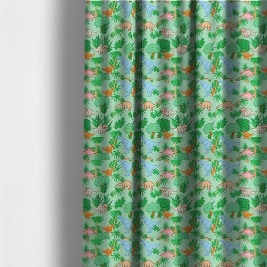 The fabric used to create these made-to-measure curtains is a repeating pattern on a light green background featuring colourful illustrated dinosaurs—including blue T-Rexes, pink Stegosauruses, beige Triceratopses, and orange sauropods—surrounded by green palm trees, bushes, and tropical foliage.