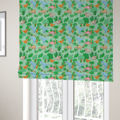 The fabric used to create these Roman blinds is a repeating pattern on a light green background featuring colourful illustrated dinosaurs—including blue T-Rexes, pink Stegosauruses, beige Triceratopses, and orange sauropods—surrounded by green palm trees, bushes, and tropical foliage.