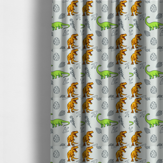 The fabric used to create these made-to-measure curtains is a repeating pattern on a light grey-blue background featuring orange Tyrannosaurus rex dinosaurs, a bright green long-necked sauropod, speckled dinosaur eggs, pinecones, footprints, and leafy sprigs.