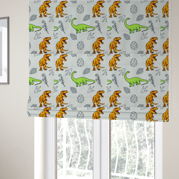 The fabric used to create these Roman blinds is a repeating pattern on a light grey-blue background featuring orange Tyrannosaurus rex dinosaurs, a bright green long-necked sauropod, speckled dinosaur eggs, pinecones, footprints, and leafy sprigs.