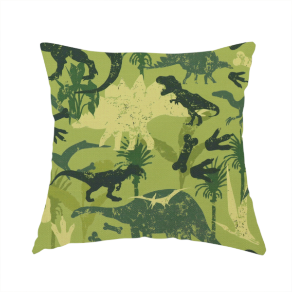 The fabric used to create this handmade cushion is a textured, distressed green and olive camouflage pattern featuring repeating silhouettes of dinosaurs, bones, footprints, and palm fronds.