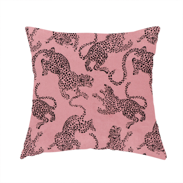 The fabric used to create this handmade cushion is a seamless repeating pattern featuring black stylized leopards or jaguars printed over a muted pink or dusty rose background. The felines are depicted in a dynamic, crouching or leaping pose with detailed spotted markings and long, curving tails.