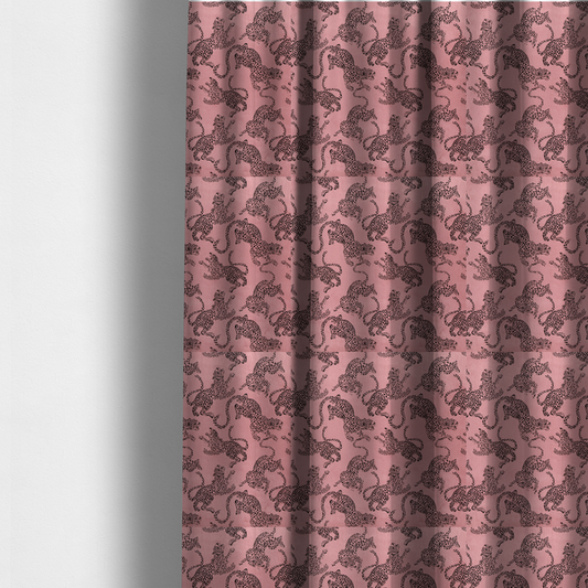 The fabric used to create these made-to-measure curtains is a seamless repeating pattern featuring black stylized leopards or jaguars printed over a muted pink or dusty rose background. The felines are depicted in a dynamic, crouching or leaping pose with detailed spotted markings and long, curving tails.