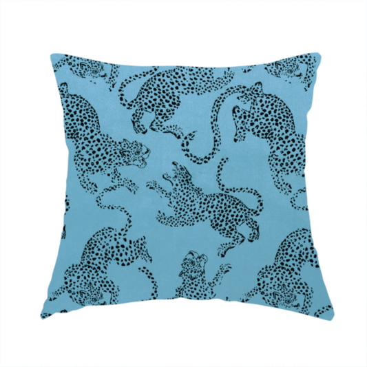 The fabric used to create this handmade cushion is a seamless repeating pattern featuring black stylized leopards or jaguars printed over a vibrant blue background. The felines are depicted in a dynamic, crouching or leaping pose with detailed spotted markings and long, curving tails.