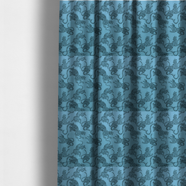 The fabric used to create these made-to-measure curtains is a seamless repeating pattern featuring black stylized leopards or jaguars printed over a vibrant blue background. The felines are depicted in a dynamic, crouching or leaping pose with detailed spotted markings and long, curving tails.