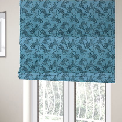 The fabric used to create these Roman blinds is a seamless repeating pattern featuring black stylized leopards or jaguars printed over a vibrant blue background. The felines are depicted in a dynamic, crouching or leaping pose with detailed spotted markings and long, curving tails.