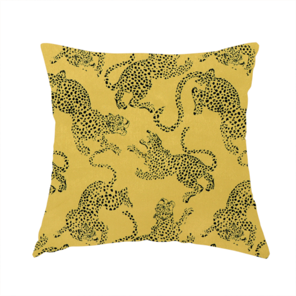The fabric used to create this handmade cushion is a seamless repeating pattern featuring black stylized leopards or jaguars printed over a mustard yellow or gold background. The felines are depicted in a dynamic, crouching or leaping pose with detailed spotted markings and long, curving tails.