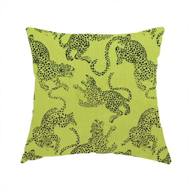 The fabric used to create this handmade cushion is a seamless repeating pattern featuring black stylized leopards or jaguars printed over a vibrant lime green background. The felines are depicted in a dynamic, crouching or leaping pose with detailed spotted markings and long, curving tails.