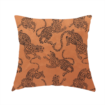 The fabric used to create this handmade cushion is a seamless repeating pattern featuring black stylized leopards or jaguars printed over a warm terracotta or burnt orange background. The felines are depicted in a dynamic, crouching or leaping pose with detailed spotted markings and long, curving tails.