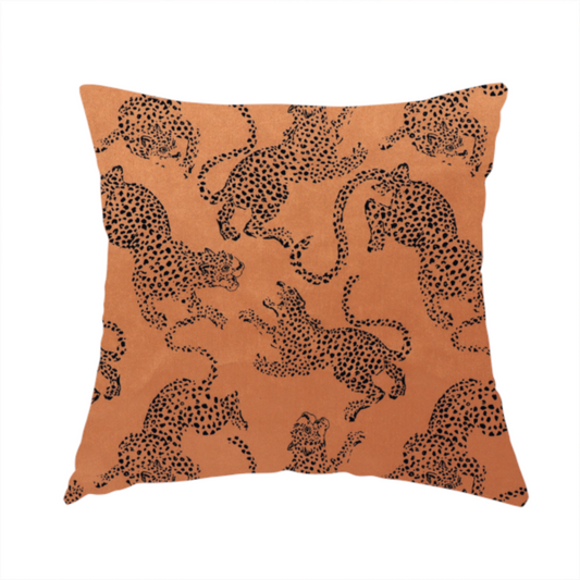 The fabric used to create this handmade cushion is a seamless repeating pattern featuring black stylized leopards or jaguars printed over a warm terracotta or burnt orange background. The felines are depicted in a dynamic, crouching or leaping pose with detailed spotted markings and long, curving tails.