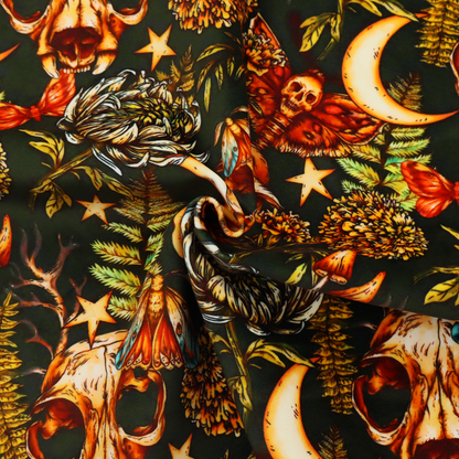 A dark and mystical repeating pattern featuring animal skulls, crescent moons, stars, moths, ferns, and chrysanthemums in warm golden and orange tones.
