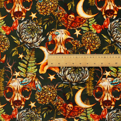 A dark and mystical repeating pattern featuring animal skulls, crescent moons, stars, moths, ferns, and chrysanthemums in warm golden and orange tones.