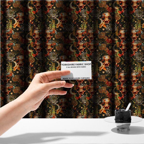 The fabric used to create these made-to-measure curtains is a dark and mystical repeating pattern featuring animal skulls, crescent moons, stars, moths, ferns, and chrysanthemums in warm golden and orange tones.
