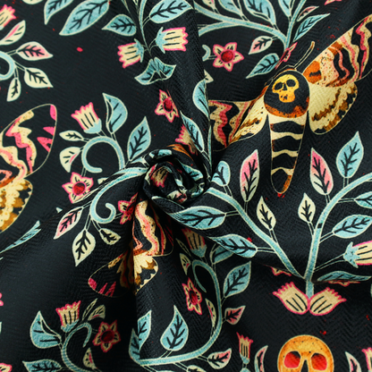 A symmetrical, damask-style repeating pattern on a black background featuring death's-head hawkmoths, human skulls, and ornate scrolling blue-green vines with pink and red flowers.