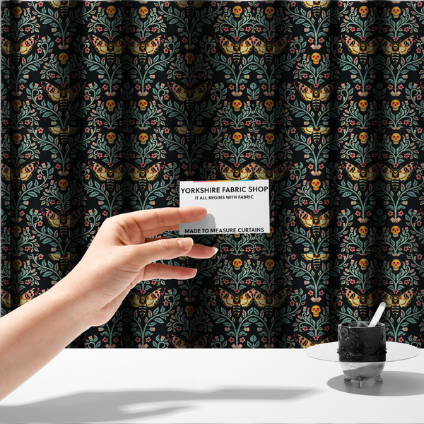 The fabric used to create these made-to-measure curtains is a symmetrical, damask-style repeating pattern on a black background featuring death's-head hawkmoths, human skulls, and ornate scrolling blue-green vines with pink and red flowers.