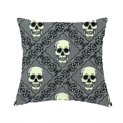 The fabric used to create this handmade cushion is a repeating pattern on a grey background featuring off-white human skulls arranged in a grid, separated by diagonal intersecting bands of ornate black lace with intricate scrollwork.