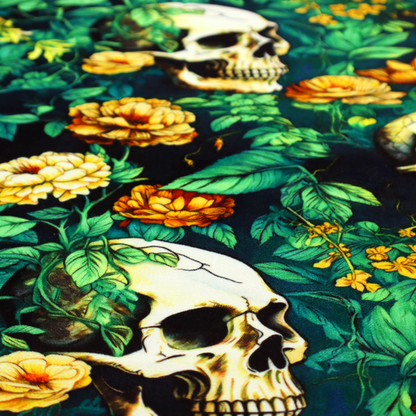A detailed repeating pattern on a dark background featuring ivory human skulls entwined with vibrant green leafy vines and blooming yellow and orange flowers.
