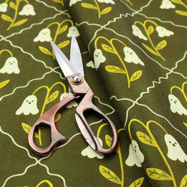 A dark olive-green vintage-style pattern featuring an ogee trellis grid framing whimsical, ghost-like floral blossoms with tiny faces.