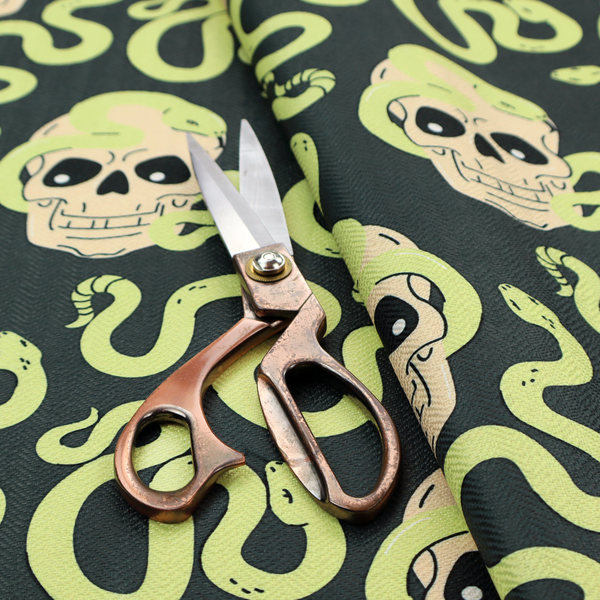 A dark charcoal pattern featuring glowing light green snakes slithering around and coiling through off-white human skulls.