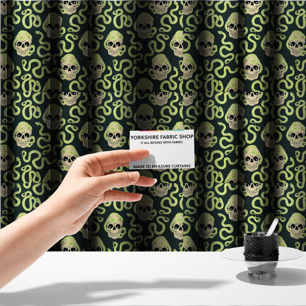 The fabric used to create these made-to-measure curtains is a dark charcoal pattern featuring glowing light green snakes slithering around and coiling through off-white human skulls.